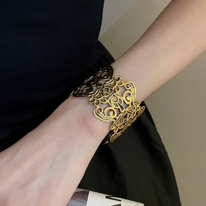 Detail of elegant gold hollowed floral cuff bracelet with intricate lace metalwork