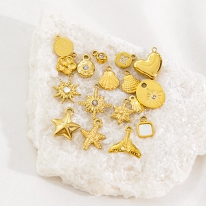 Polished 14K gold-plated stainless steel charms in assorted shapes on marble