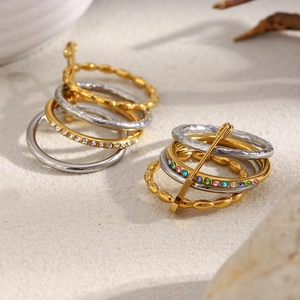 Detailed close-up of 18K gold and silver rings with colored zircon on white sand