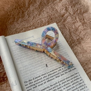 Detail of marble pattern acetate hair claw clip with gold spring on a book