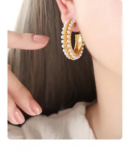 Close-up of gold-plated irregular C-shape earrings with inlaid pearls on a female model