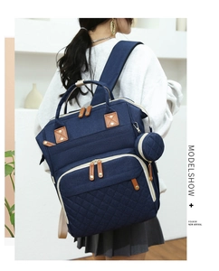 Detail of dark blue quilted diaper backpack with side coin purse and gold hardware