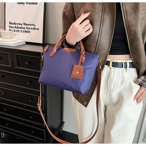 Detail of purple nylon tote bag with leather straps worn by model in a stylish interior