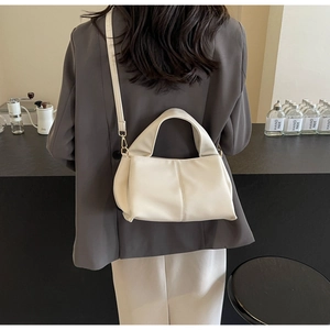 Detailed view of a cream white leather crossbody bag with adjustable shoulder strap