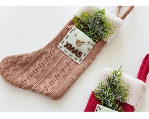 Detail of knitted Christmas stockings in red and brown with XMAS pocket and pine accents