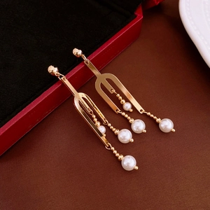 Boucles d'oreilles pendantes géométriques en perles dorées sur écrin en velours rouge