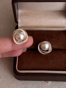 Macro shot of gold pearl stud earrings with zircon halo on a velvet jewelry box
