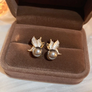Detailed shot of gold butterfly pearl earrings nestled in a brown velvet jewelry box