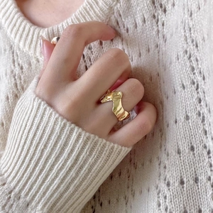 Detail of a 925 sterling silver irregular wave ring worn on finger with a knit background