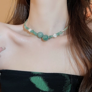 Dettaglio della collana di perline di giada verde con fiori in metallo sul collo della modella