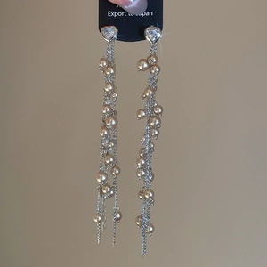 Dettaglio macro di orecchini a cuore con cristalli ed eleganti nappe di perle