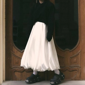 Detail of white satin bubble midi skirt with glossy finish and curved hemline