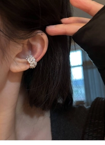 Close-up of a silver-colored zircon flower ear cuff worn on the upper ear bone