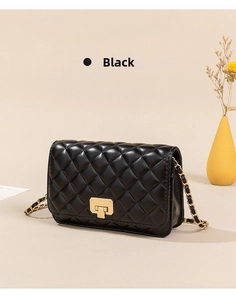 Close-up of black quilted chain bag with gold metal lock and leather strap detail