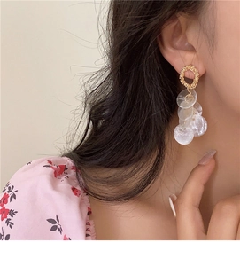 Macro detail of round shell tassel earrings with golden rings on model's ear