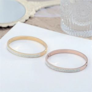 Detail showing two gold and rose gold bangles with micro-pave crystals on a soft background