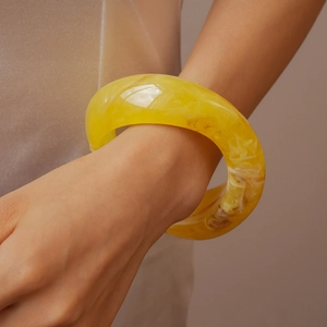 Macro shot of chunky yellow resin bangle with amber marble texture on wrist