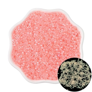 Luminous glass seed beads for DIY jewelry in pink and gold tones displayed in a petal dish