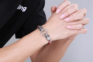 Close-up of men's skull bracelet with red accents and black braided cord on wrist