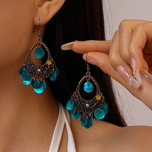 Detail of bohemian drop earrings with turquoise shells and intricate vintage bronze cutouts