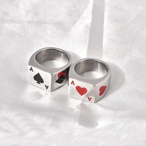 Close-up of Ace of Spades and Hearts stainless steel rings on white silk background