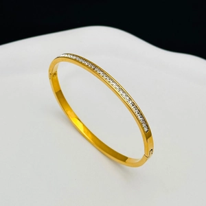 Detail of gold titanium bangle featuring channel set square zircon stones on wavy tray