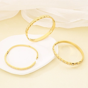 Three 18K gold-plated stainless steel bangles with sparkling zircon crystals on marble