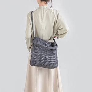 Gray woven PU leather tote bag shown on model with spacious bucket design and soft texture