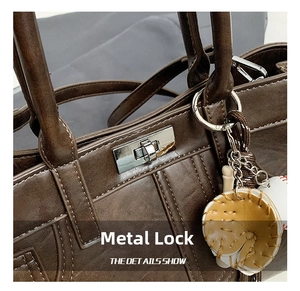 Détail du fermoir en métal argenté et du cuir marron texturé sur un sac à main élégant