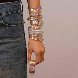 Close-up of stacked iridescent acrylic geometric bracelets with vibrant metallic colors
