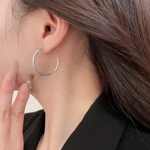 Close-up of minimalist silver twisted hoop earrings on a model with a polished finish