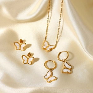 Close-up of gold butterfly jewelry set including necklace and earrings on silk