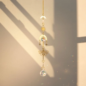 Detail of brass butterfly suncatcher with crystal ball creating rainbow light on wall