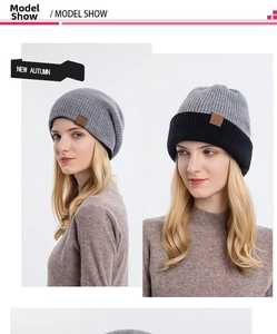 Detail of grey knitted beanie with ribbed texture and brown leather logo patch on the side