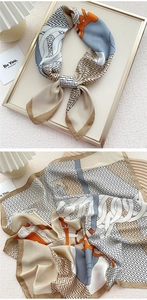 Detailed view of geometric printed satin scarf with abstract patterns in orange and beige