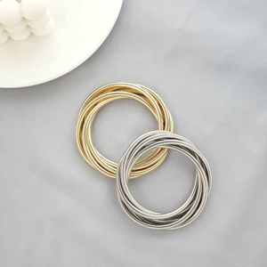 Close-up of multilayer spiral snake bone texture bracelets in gold and silver finishes