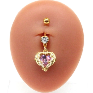 Detail of a gold angel wing belly ring with pink heart crystal on a model