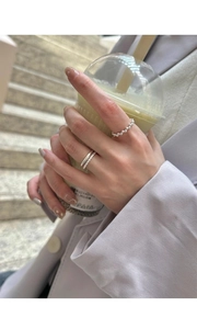 Detail of s925 silver minimalist bean and smooth rings worn while holding a cup