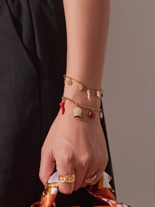 Détail d'un bracelet en acier doré avec cloches en zircone et breloque coccinelle au poignet