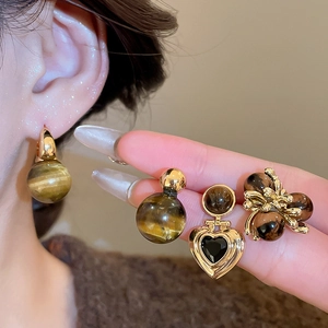 Detailed macro view of vintage tiger eye stone earrings in heart and flower designs