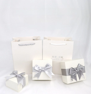 White jewelry gift boxes and matching paper bags with silver satin bow decoration