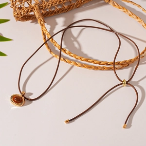 Detail of resin oval pendant necklace with golden metal edge and brown cord