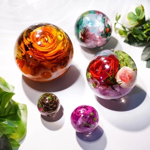 Nahaufnahme von klaren Harzkugeln mit echten Trockenblumen wie Rosen und Hortensien