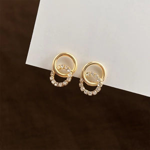 Macro detail of gold double hoop clip-on earrings featuring sparkling white rhinestones