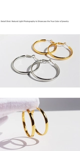 Detail shot of large polished metal hoop earrings in gold and silver finish