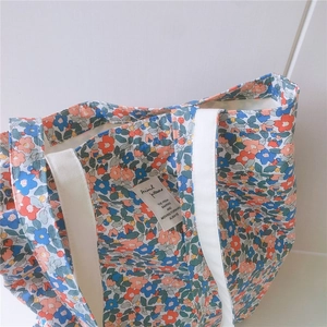 Close-up of floral cotton tote bag showing blue and red patterns with stitched label