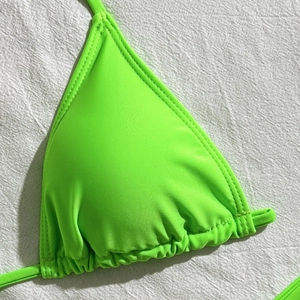 Close-up of neon green bikini top showing detailed stitching and mesh fabric texture