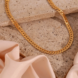 Detailed close-up of a 18K gold-plated flat Cuban chain necklace on a stone background