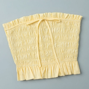 Detail of light yellow smocked tube top with drawstring bow and ruffled edges