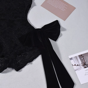 Close-up of black lace bodysuit featuring exquisite velvet bow and intricate texture details